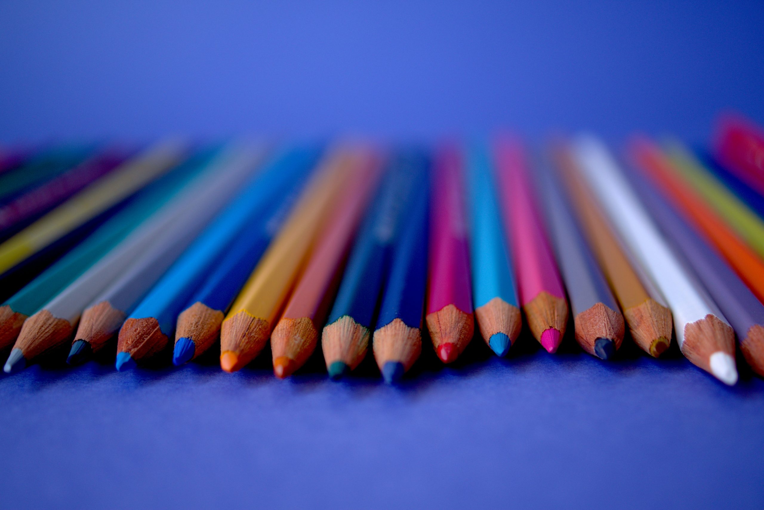 A row of colored pencils on a blue surface