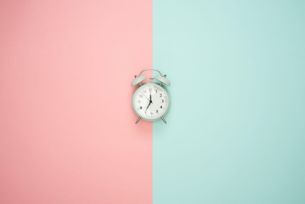 An alarm clock with a pink and blue background