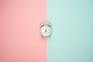 An alarm clock with a pink and blue background