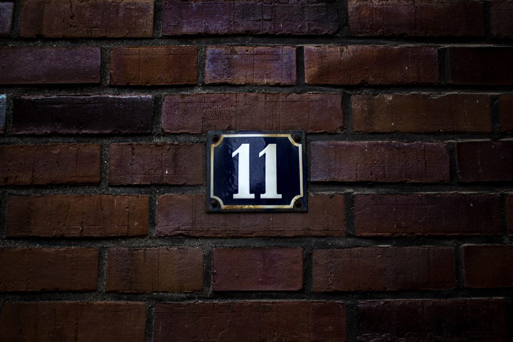 Number 11 painted on a red brick wall