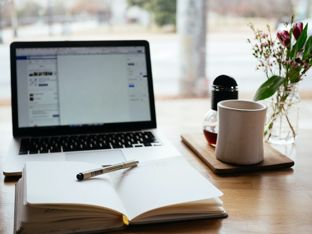 A table with a notebook, open notebook, and a cup of tea