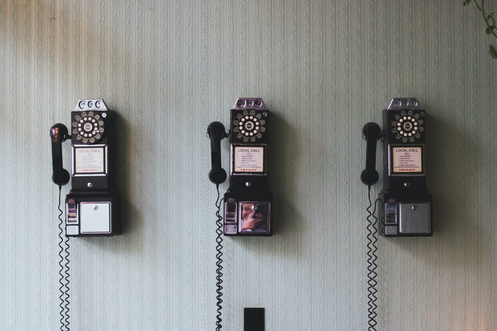 Miniature black payphones on white wall.